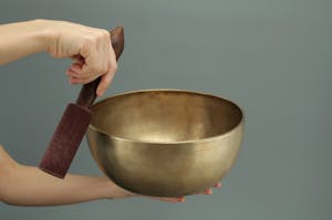 Close-up of a hand holding a Tibetan singing bowl used for meditation and relaxation.